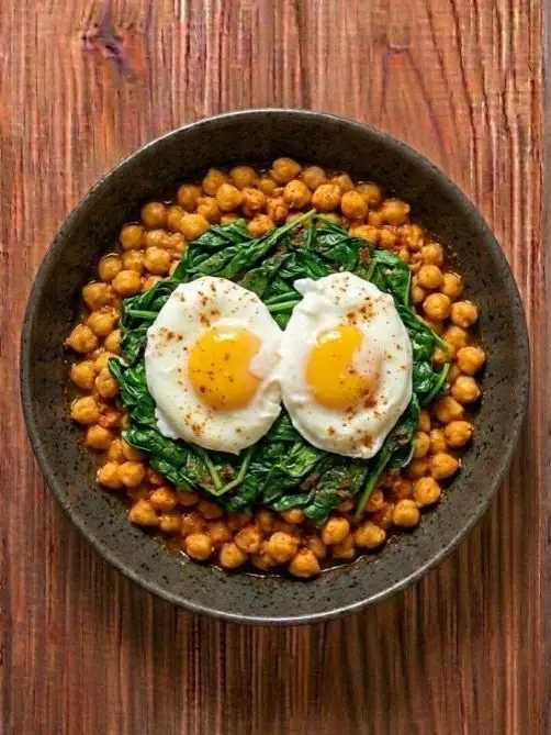 Huevos poché sobre cama de garbanzos con espinacas